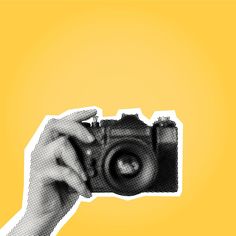 a person's hand holding up a camera with the lens pointed upward, in front of a yellow background