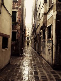 an alley way with old buildings and graffiti on the walls, as well as wet pavement