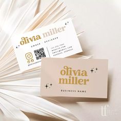 two business cards sitting on top of each other in front of a white paper fan