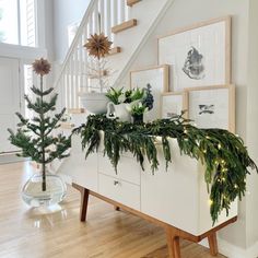 a christmas tree sitting on top of a white dresser next to a stair banister