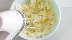 a person mixing food in a bowl with a blender