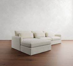 a white couch sitting on top of a hard wood floor next to a wall in an empty room