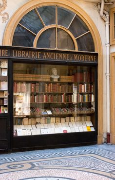 an old library with many books in it's glass display case on the sidewalk