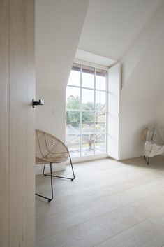 an empty room with a chair and large window