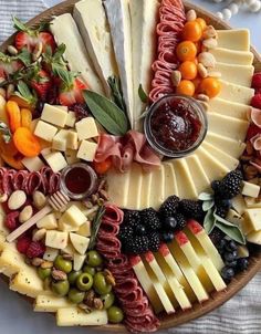 a platter filled with cheese, meats and fruit