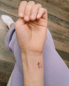 a woman's arm with a small cross tattoo on the left side of her wrist