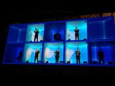 several people are standing on stage in front of blue cubes with different lighting effects