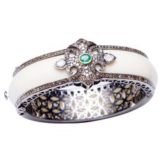 A stunning cuff bracelet in white Bakelite bordered on both sides with pave` set diamonds. The top features additional pave` set diamonds with an oval, faceted emerald and two rose-cut diamonds on each side. Inside circumference is 6 1/8th inch. Perfect for those small wrists. The cuff itself is an oval shape which helps to keep the lovely workmanship and stones on the top of the wrist. Carat weight of diamonds is 4.10; emerald is .35 carats. John Hardy, Rose Cut Diamond, Girls Best Friend, Both Sides, Rose Cut, Oval Shape, Cuff Bracelet, Cuff Bracelets, Diamond Cuts