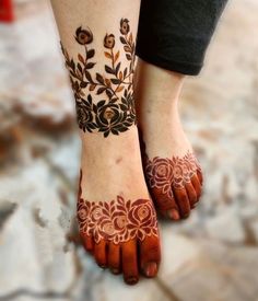 two feet with hendi tattoos on them, one has flowers and the other has leaves