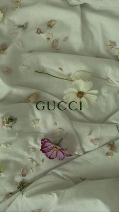 a white bed with flowers on it and the words gucci written in cursive writing