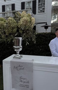 a man standing next to a vase with flowers in it on top of a table