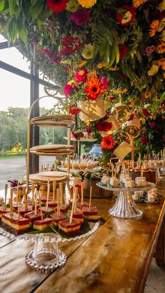 a long wooden table topped with lots of plates and trays filled with desserts