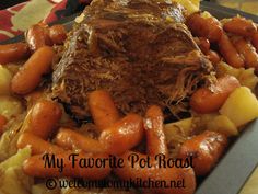 a roast beef with carrots and potatoes in a pan on top of a table