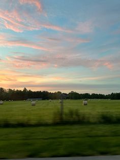 a field with hay bales in the foreground at sunset