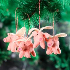 three pink stuffed animals hanging from a christmas ornament on a green tree branch