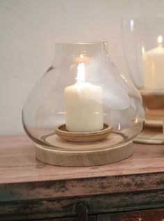 a white candle in a glass vase on a wooden table