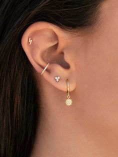 a woman's ear is shown with two small diamond earrings on top of it