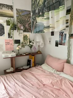 a bedroom with pink sheets and pictures on the wall