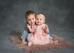 two young children sitting on a rug with their arms around each other