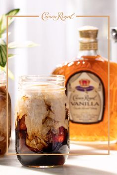 two jars filled with food sitting on top of a table next to bottles of liquor