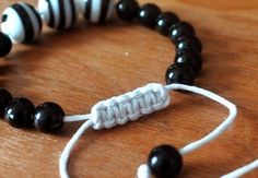 a black and white beaded bracelet on a wooden table with beads attached to it