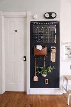 a chalkboard with some plants hanging on it and two clocks above the door that are attached to the wall