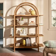 a wooden shelf with books and vases on it in a room next to a window