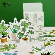 some plants are sitting on the table with paper cutouts in front of them that look like they have been placed together