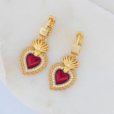 Delicate and Versatile: The small size and classic design make these earrings perfect for everyday wear or special occasions. Shiny: The gold plating and white zirconia create a beautiful shine that catches the light. Meaningful Symbol: The red enamel hearts are a constant reminder of God's love and grace. The Everlasting Love Heart Earrings are a charming and symbolic addition to your collection of devotional jewelry. These earrings showcase dainty red enamel hearts, symbolizing God's love, bat Gold Cubic Zirconia Earrings With Heart Charm, Elegant Gold Plated Huggie Earrings For Valentine's Day, Love For God, Catholic Jewelry, Catholic Gifts, Everlasting Love, Religious Jewelry, Gold Plated Earrings, Heart Earrings