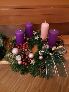 a wreath with purple candles and christmas decorations