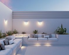 a living room with white couches and potted plants