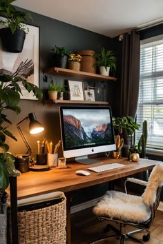 a desk with a computer on top of it next to a window and potted plants