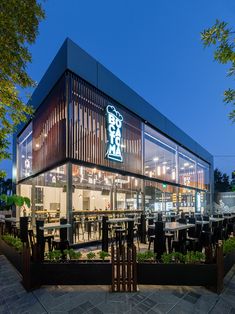 an outdoor dining area with tables, chairs and plants in the foreground at night