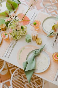 the table is set with plates, napkins and flowers