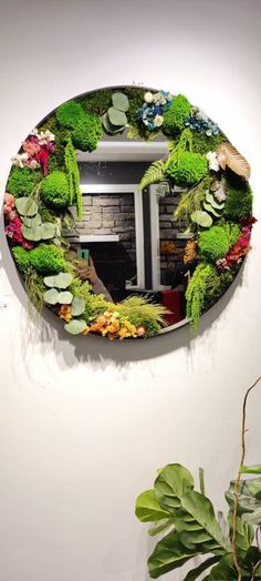 a mirror that is on the wall with flowers and plants in front of it's reflection