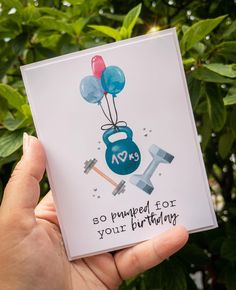 someone holding up a birthday card that says, so pumped for your birthday with balloons and dumbble weight