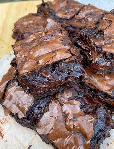 some brownies are sitting on top of a piece of parchment paper with chocolate frosting