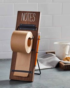 a roll of toilet paper sitting on top of a wooden holder next to a cup