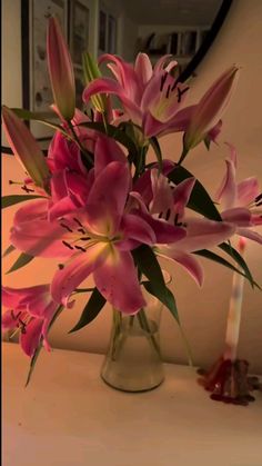 a vase filled with pink flowers sitting on top of a table next to a candle