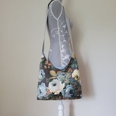 I've created this handmade, slouchy bag from a vintage Sanderson reclaimed linen union floral fabric.  It features cream and blue coloured cabbage roses and daisies on a grey background.   The bag is fully lined with a contrasting spotted cotton fabric and fastens with a magnetic clasp.  It has a grey coloured webbing strap. Please note pattern placement may vary. It's a great size and very versatile with a strap long enough to wear on the shoulder or across the body.  The strap measures 94cm lo Vintage Floral Print Shoulder Bag, Handmade Vintage Cotton Shoulder Bag, Spring Vintage Floral Print Shoulder Bag, Bohemian Floral Print Tote Shoulder Bag, Vintage Floral Print Shoulder Bag For Spring, Bohemian Tote Shoulder Bag With Floral Print, Bohemian Shoulder Bag With Floral Print Tote, Vintage Floral Print Tote Shoulder Bag, Handmade Vintage Hobo Bag