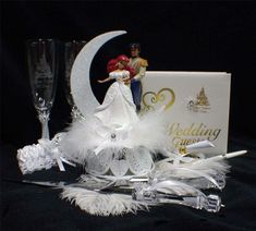 a bride and groom figurine sitting on top of a table next to champagne flutes