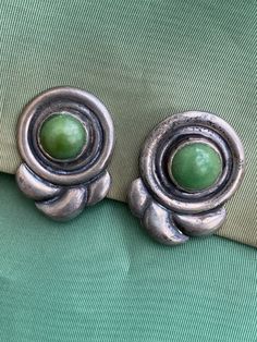 "Fabulous MCM modernist design Mexican jade, green stone Sterling silver Screw back Light - 7 grams each Nice secure clips Beautiful patina Materials: sterling silver, Mexican jade Measurements: .75 x 1.25\" (1.90 x 3.17cm) Provenance: mid1940s Stamp: Silver, Mexico Condition: Very good vintage. No issues of note. We've just given a quick wipe with jewelry cloth, leaving polishing to the next owner. See pics. Sold as is. Check measurements and/or convo with ANY questions prior to purchase as there are no returns. 20230617J3091" Green Metal Clip-on Earrings, Green Clip-on Metal Earrings, Green Metal Clip-on Jewelry, Green Clip-on Metal Jewelry, Mid-century Green Formal Jewelry, Vintage Jade Round Earrings, Vintage Green Jade Earrings, Retro Green Clip-on Earrings, Vintage Green Sterling Silver Earrings