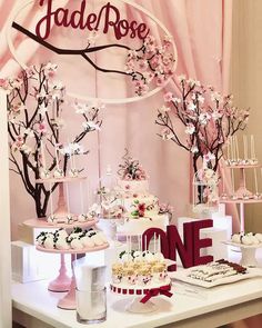 a table topped with cakes and desserts on top of a white table covered in pink flowers