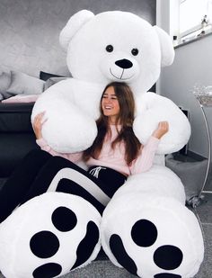 a woman sitting on the floor with a giant teddy bear