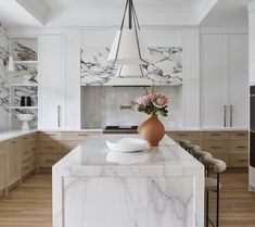 a large kitchen with marble counter tops and white cabinetry, along with wooden flooring