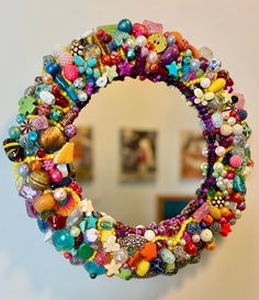 there is a colorful beaded wreath hanging on the wall in front of a mirror