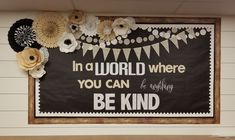 a bulletin board with paper flowers on it and a quote written in the center that says, in a world where you can be anything be kind