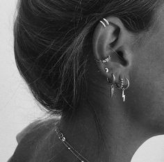 black and white photograph of a woman's ear with multiple piercings on it