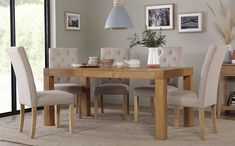 a dining room table with grey chairs and pictures on the wall in the back ground