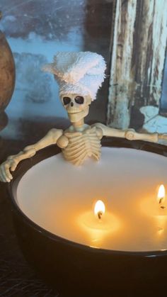 a skeleton sitting in a bowl with candles